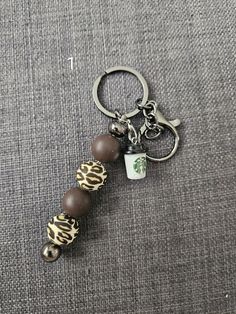 a starbucks keychain with coffee and leopard print beads on the bottom is sitting on a gray carpet