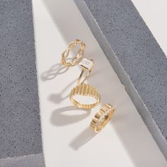 two gold rings sitting next to each other on top of a white surface and one has a diamond in the middle