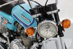 the front end of a blue motorcycle with its lights on