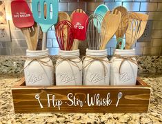 four mason jars with whisk utensils in them on a kitchen counter