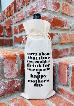 a wine bag with the words happy mother's day printed on it sitting against a brick wall