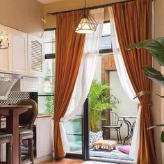 a living room filled with furniture next to a window covered in curtains and drapes