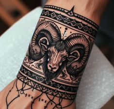 a hand with a black and white tattoo design on it's left wrist, holding a ram