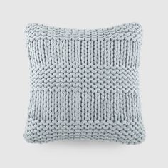 a blue knitted pillow sitting on top of a white wall