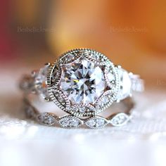 a close up view of a diamond ring on top of a white cloth with the background blurred