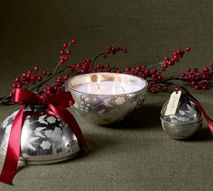 two candles are sitting next to each other on a table with red ribbon around them