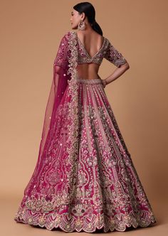 a woman in a pink and gold lehenga, with her back to the camera