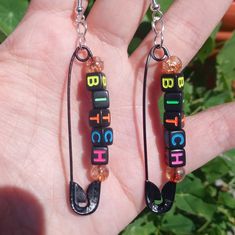 a pair of earrings that are made out of legos and beads with words on them