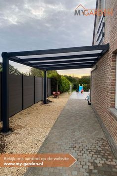 an outdoor covered walkway next to a brick building with a blue sky in the background