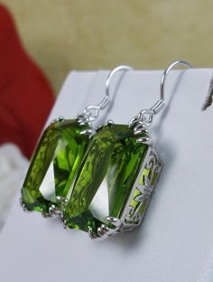 Simulated Green Peridot Earrings Description LUV Design#109 Made to Order These are lovely Art Nouveau Inspired sterling silver filigree earrings. The silver of these earrings has a gorgeous Antique patina to it. These 26ctw flawless rectangle-cushion-cut man-made/simulated Green Peridot gems are 18mm (just over 3/4th of an inch) by 13mm (1/2 inch) in size each. The earrings are 1 3/8th inches long. Notice the beautiful swirl floral filigree of the settings. This is a well made beautiful pair of Rectangle Cushion, Floral Filigree, Order Design, Peridot Earrings, Filigree Earrings, Sterling Silver Filigree, Green Peridot, Silver Filigree, Cushion Cut