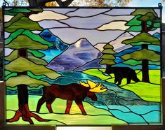 a stained glass window with a moose and bear in the woods on it's side