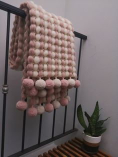 a pink and white blanket is hanging on a rail next to a potted plant