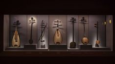 an assortment of musical instruments on display in a case with lights and shadows behind them