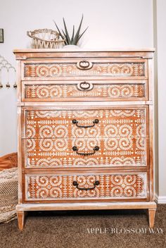 an old dresser has been painted with white and brown designs on the top, along with a potted succulent plant