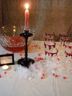 a table topped with lots of wine glasses next to a candle and some candlesticks