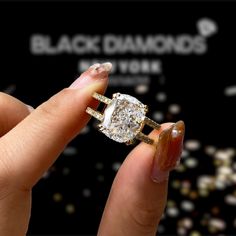 a woman's hand holding an engagement ring in front of a black diamond sign