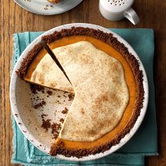 a pie sitting on top of a wooden table next to a plate with a slice missing