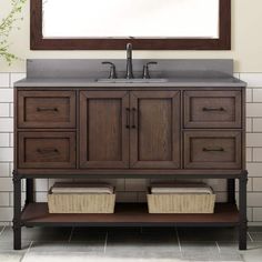 a bathroom vanity with two baskets under the sink and a large mirror above it,