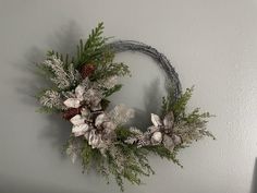 a wreath hanging on the wall with pine cones