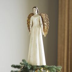 an angel figurine sitting on top of a christmas tree