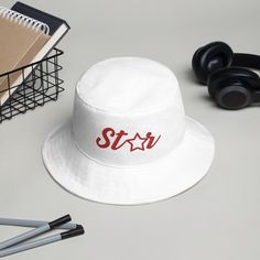 I am so excited to introduce my newly designed STAR bucket hat. It is part of my Be A Star Where You Are apparel collection. Now you can combine practicality, comfort, and fashion in one. Keep the sun out of your eyes with this 100% cotton twill bucket STAR hat. Made with cotton fabric and sewn eyelets are sure to help you stay cool during any activity, be it a stroll in the park or an intense game of sports. Additional Details: * 100% cotton twill * 3 ¾″ (7.6 cm) crown * 2 ¼″ (5.1 cm) brim * On Star Hat, White Bucket Hat, Red Embroidery, Fisherman Hat, You Are, Trucker Cap, Cotton Twill, Caps Hats, Bucket Hat