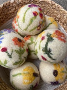 several white balls with colorful flowers on them in a basket