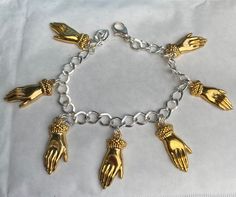 "Victorian style cuffed hand gold tone charm bracelet. Elegant with the hand being the heart of special occasions like engagement or weddings, mystical for millennia or simply to give someone a hug  Using 7 charms,of hands The bracelet has a lobster claw clasp. A lovely bracelet , an ideal quirky present . There are also co-ordinating earrings listed for pierced ears as well as a brooch See also silver tone versions  All the charms are single sided. Measurement : The charm is 2.5 cm / 1\" long. The chain is available in lengths 19-21cm If you need a shorter chain please contact me but the open links mean that you can hook in the lobster claw clasp where it suits. If no length is specified I will send the 20cm standard length" Gold Symbolic Charm Bracelet, Symbolic Gold Charm Bracelet, Gold Chain Bracelet With Extender In Sterling Silver, Hand Cast Metal Bracelets Gift, Gold Symbolic Metal Charm Bracelet, Gold Charm Bracelet With Symbolic Dangling Charms, Gold Sterling Silver Symbolic Bracelet, Gold Symbolic Sterling Silver Bracelet, Gold Symbolic Bracelet In Sterling Silver