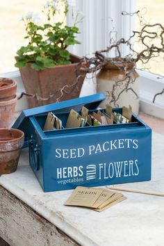 seed packets are in a blue box on a window sill