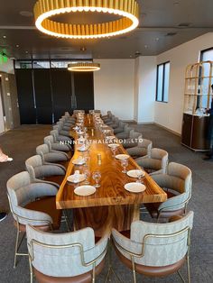 a long wooden table with chairs around it in a conference room, next to a chandelier