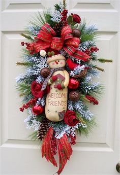 a christmas wreath with a teddy bear hanging on the front door