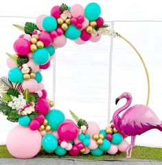 a pink flamingo is standing in front of a balloon arch decorated with flowers and balloons