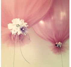 two pink and white balloons with flowers on the top one is attached to a wall