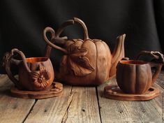 three wooden teapots with carved faces and handles