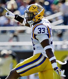 a football player wearing a yellow uniform and holding his arm out to the sideline