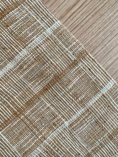 a close up view of the fabric on a wooden table top with white and brown lines