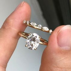 a person holding a diamond ring in their left hand and the other hand with it's fingers