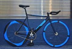 a bike with blue rims parked on the side of a street next to a garage door