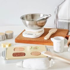 a kitchen scale, measuring cup and other items on a white counter top with a wooden spoon