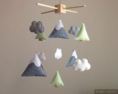 a mobile with clouds and trees hanging from it's sides in the shape of mountains