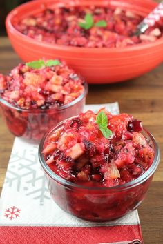 two bowls filled with cranberry sauce on top of a red napkin and silverware