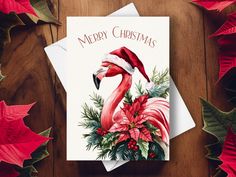 a christmas card with a flamingo wearing a santa hat and poinsettis