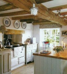 an old fashioned kitchen with white cabinets and wooden beams on the ceiling is well lit by candles