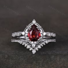 a close up view of a ring with a red stone in the center and white diamonds around it