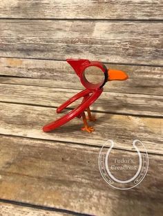 a small red bird sitting on top of a wooden table