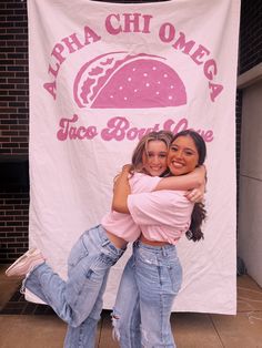 two women hugging each other in front of a banner