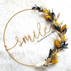 the word smile written in gold is surrounded by dried flowers and feathers on a white background