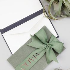 an open envelope with a green bow and name on it, next to a succulent plant