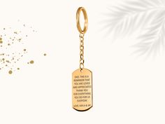 a gold keychain with a quote on it and a palm leaf in the background