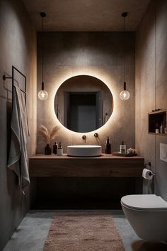 a bathroom with a round mirror above the sink and lights on the wall over the toilet