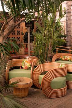 wicker chairs and stools are arranged on the ground in front of palm trees